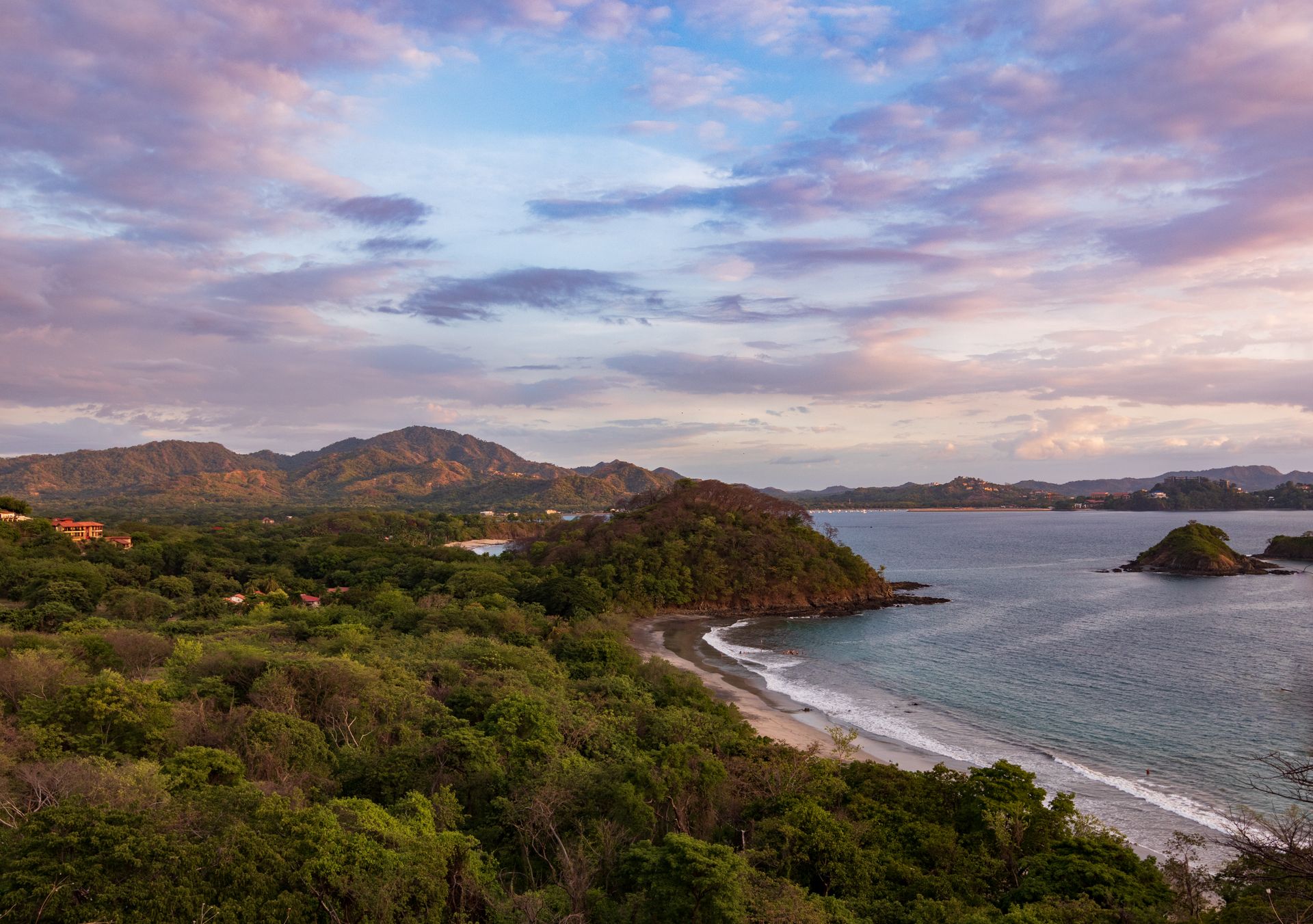 Lush green hillsides above a Pacific cove at golden hour on Costa Rica's Guanacaste coast